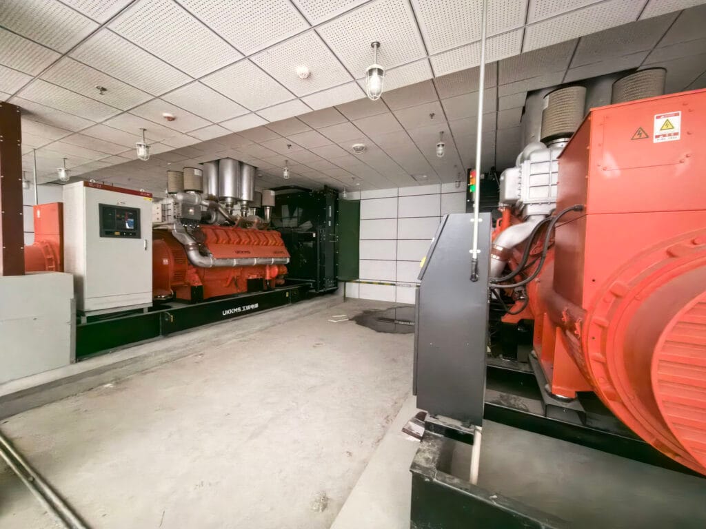 Third perspective of generator room showing complete emergency power infrastructure and control systems