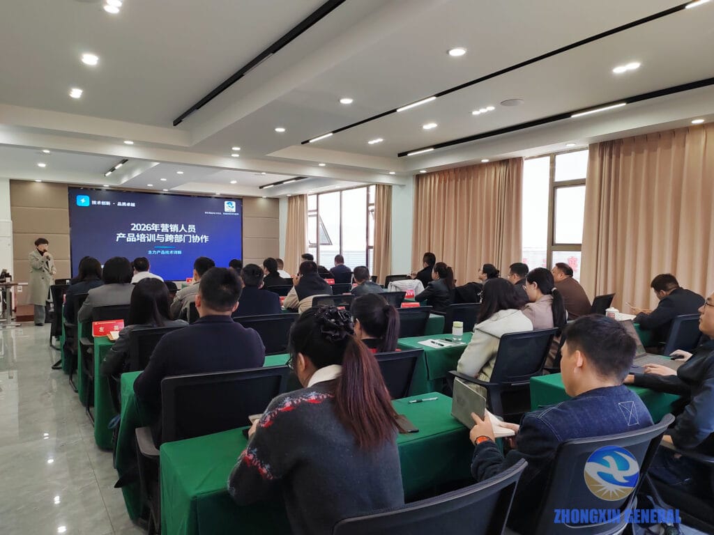 Wide-angle view of the full Zhongxin General sales training session, showing approximately 25–30 staff members seated in the conference room with the trainer presenting at the front, screen reading '2026 Sales Staff Product Training and Cross-Department Collaboration'.