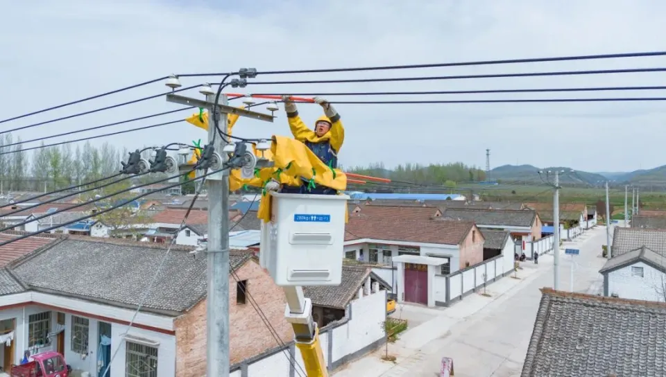 Operator in insulated bucket truck making live HV connection at overhead line — mobile substation bypass, Baoji Shaanxi April 2026