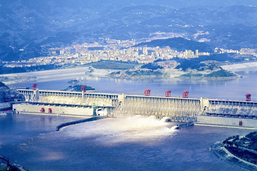 Mid-altitude aerial view of Three Gorges Dam with city and surrounding landscape visible in background