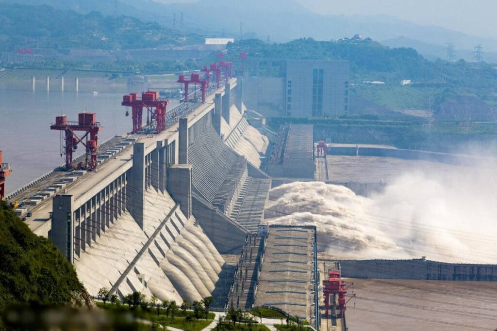 Side view of Three Gorges Dam concrete structure with spillway gates open and water discharging at high volume