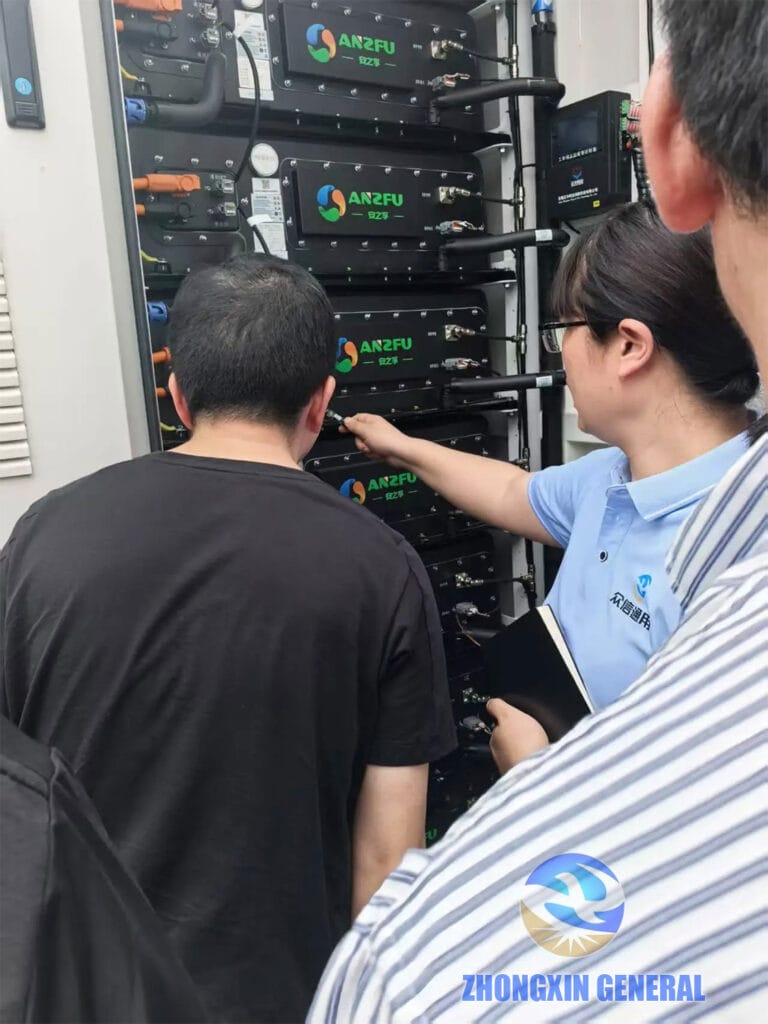 Technician explaining the interior of a battery container to visiting delegates at the Xinjin storage project