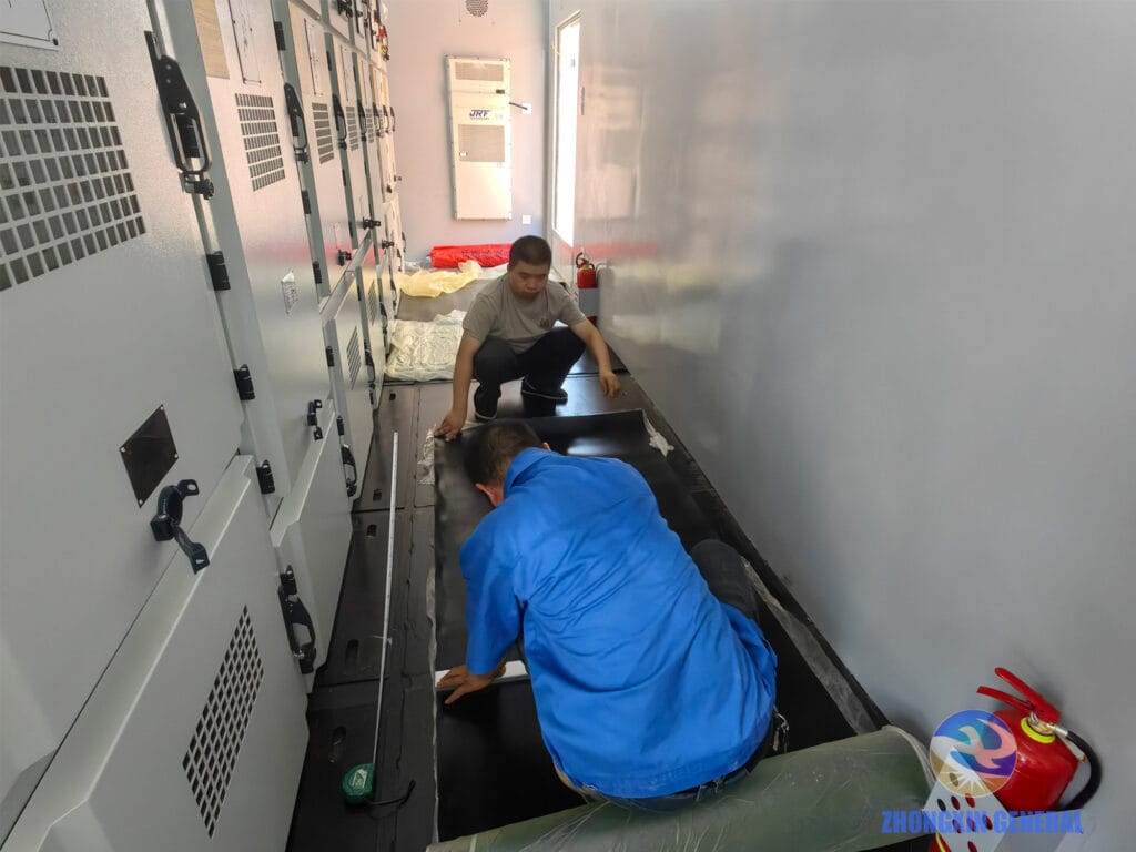 Technicians cutting insulation matting inside prefabricated cabin