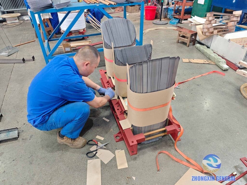 Workers installing insulation paper accessories on transformer core