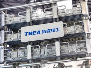 TBEA high-voltage power transformer on display at an industry exhibition, showcasing the company's flagship power transmission equipment with its signature silver cooling radiators and precision-engineered metal piping