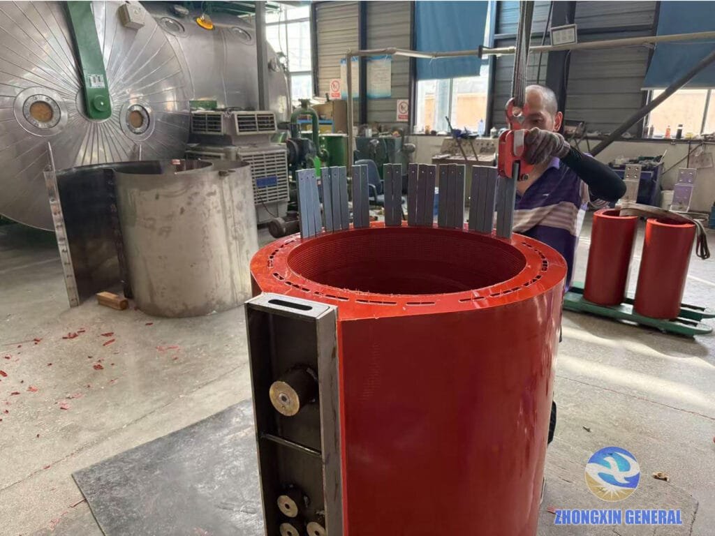 technician removing air duct strips from cast resin winding after epoxy curing with vacuum drying tank in background