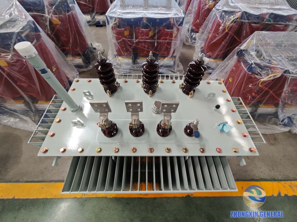 Top overhead view of finished 630 kVA oil‑immersed distribution transformer, conservator tank, HV‑LV terminals, lifting lugs