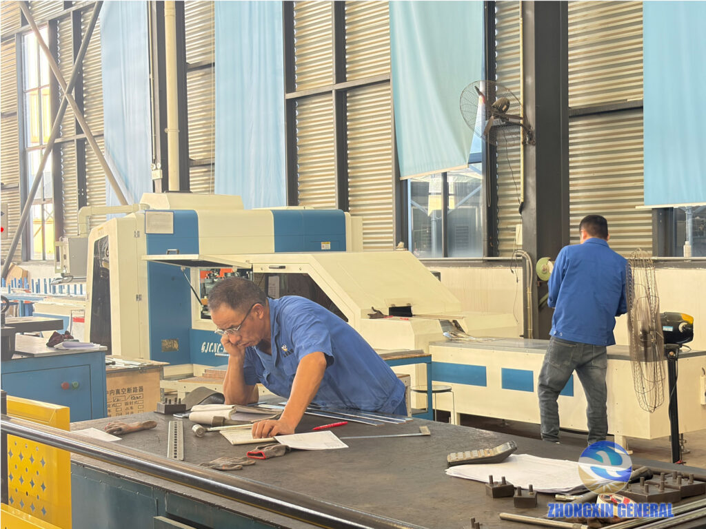 Technician checking fabrication drawings at a CNC punching station in the switchgear cabinet sheet-metal workshop